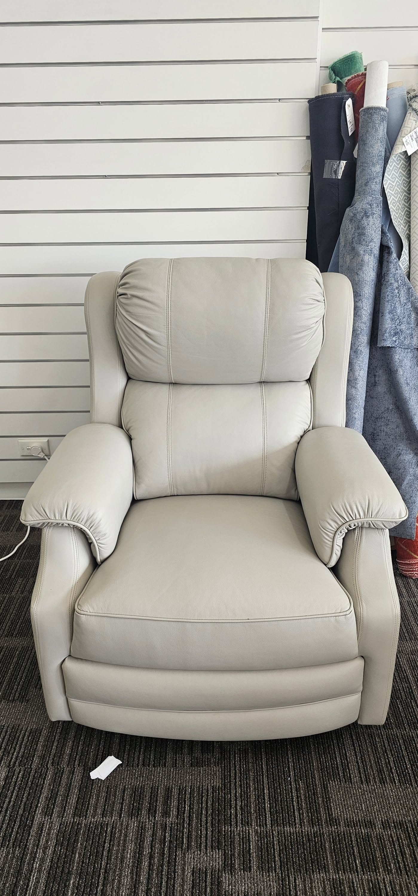 Light grey leather armchair with stitched panels and padded arms